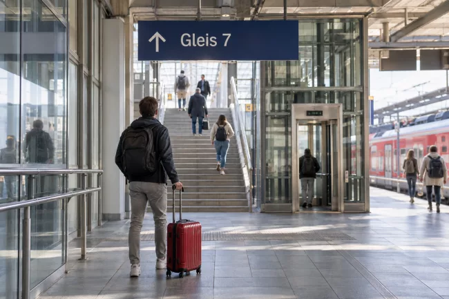 Пассажир у указателя Gleis 7 на немецком вокзале